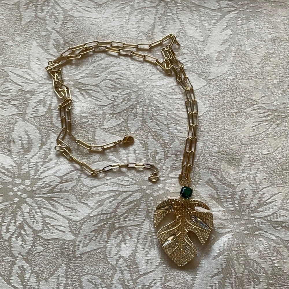 Swarovski gold tone leaf pendant with white and green crystals.